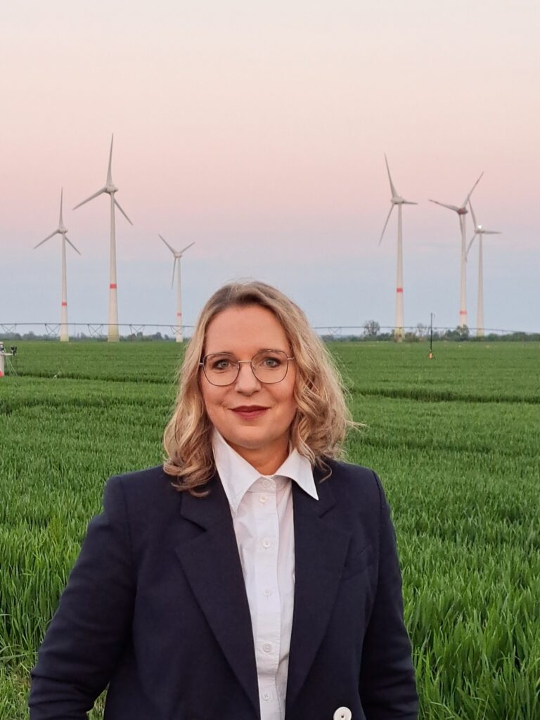 Prof. Dr. Claudia Kemfert vor einem Feld mit Windkraftanlagen. Bild: privat